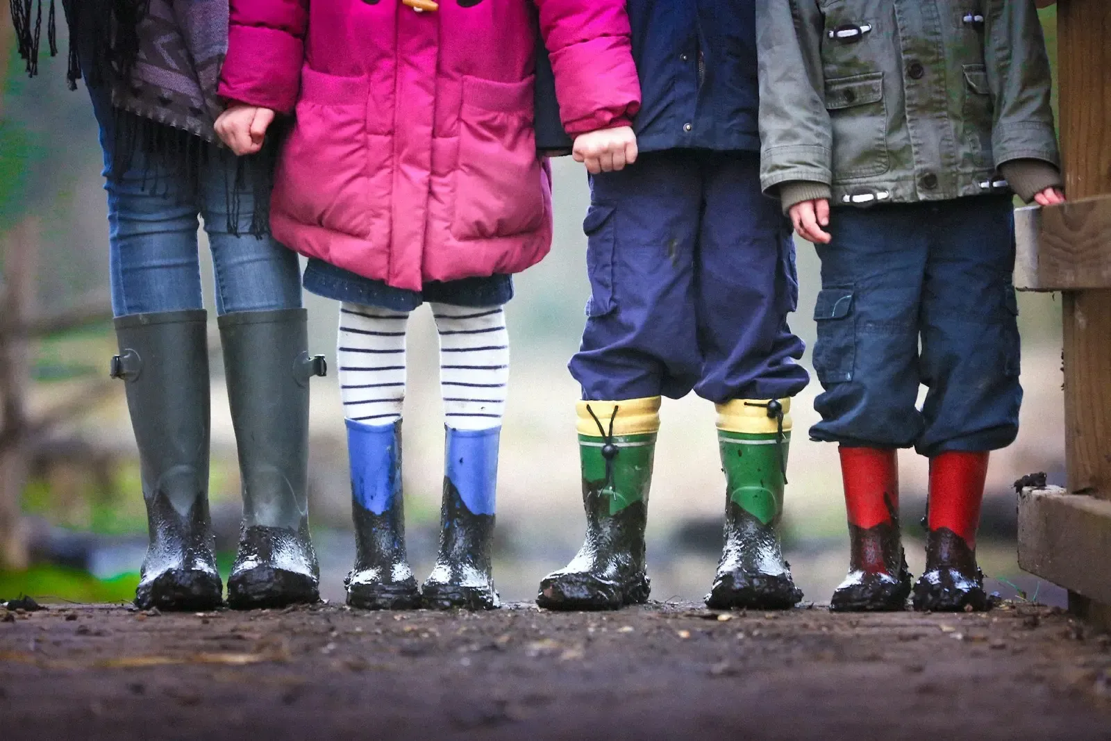 Children in colorful rain boots standing together outdoors