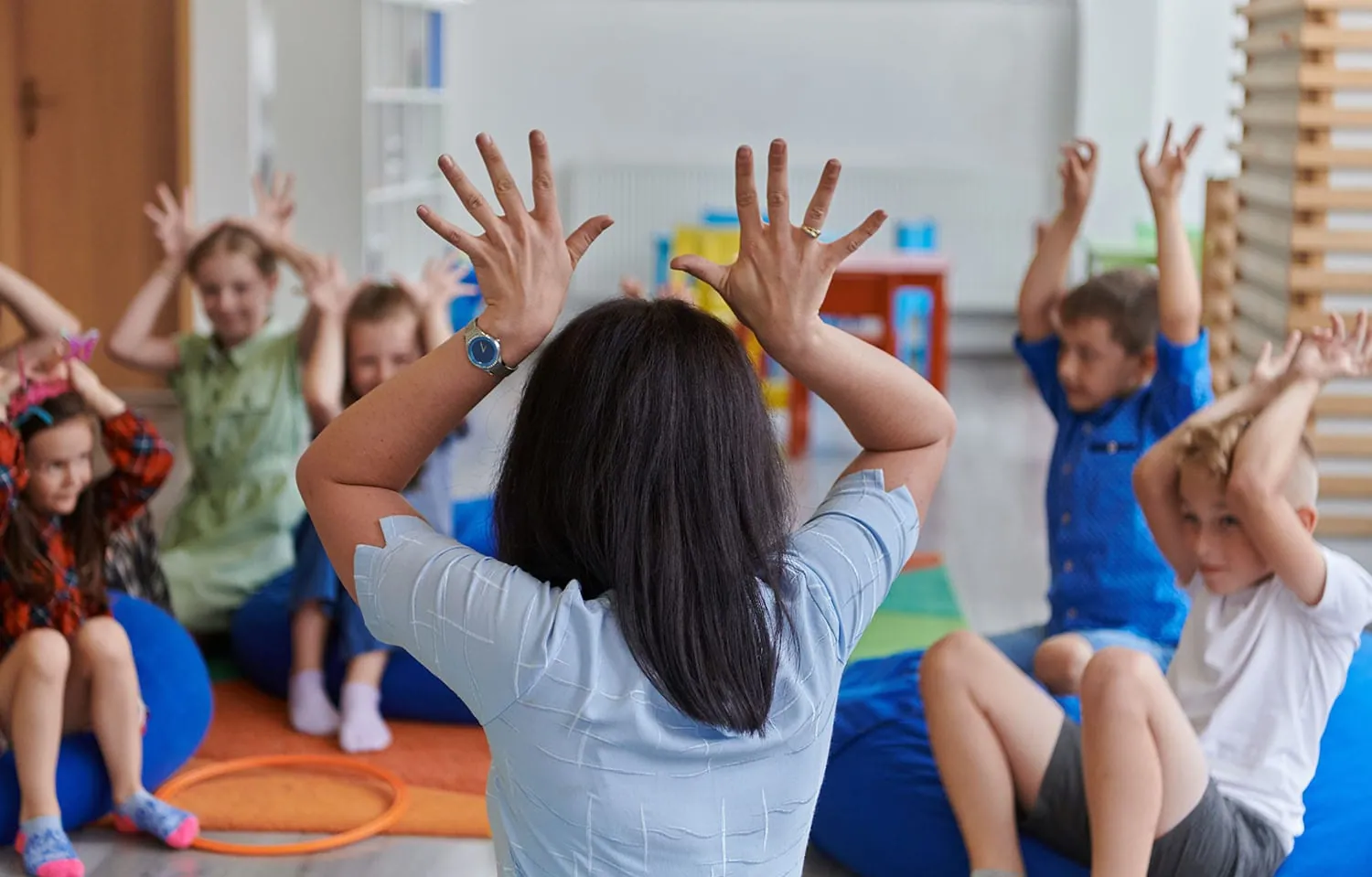 Educator leading a group hand-movement activity with children