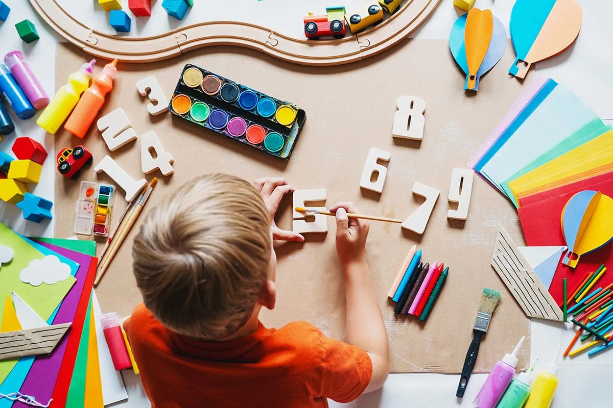 Child painting wooden numbers in an art and craft activity